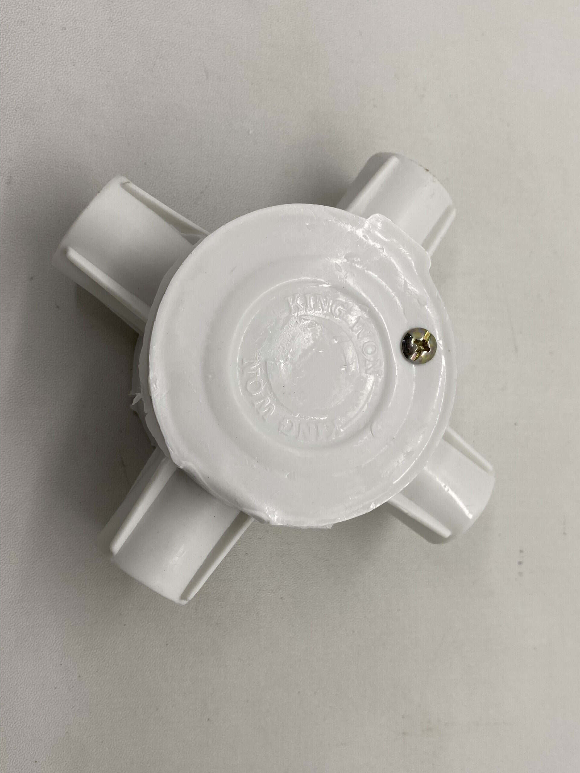 White plastic plumbing fitting with multiple outlets for water connections.